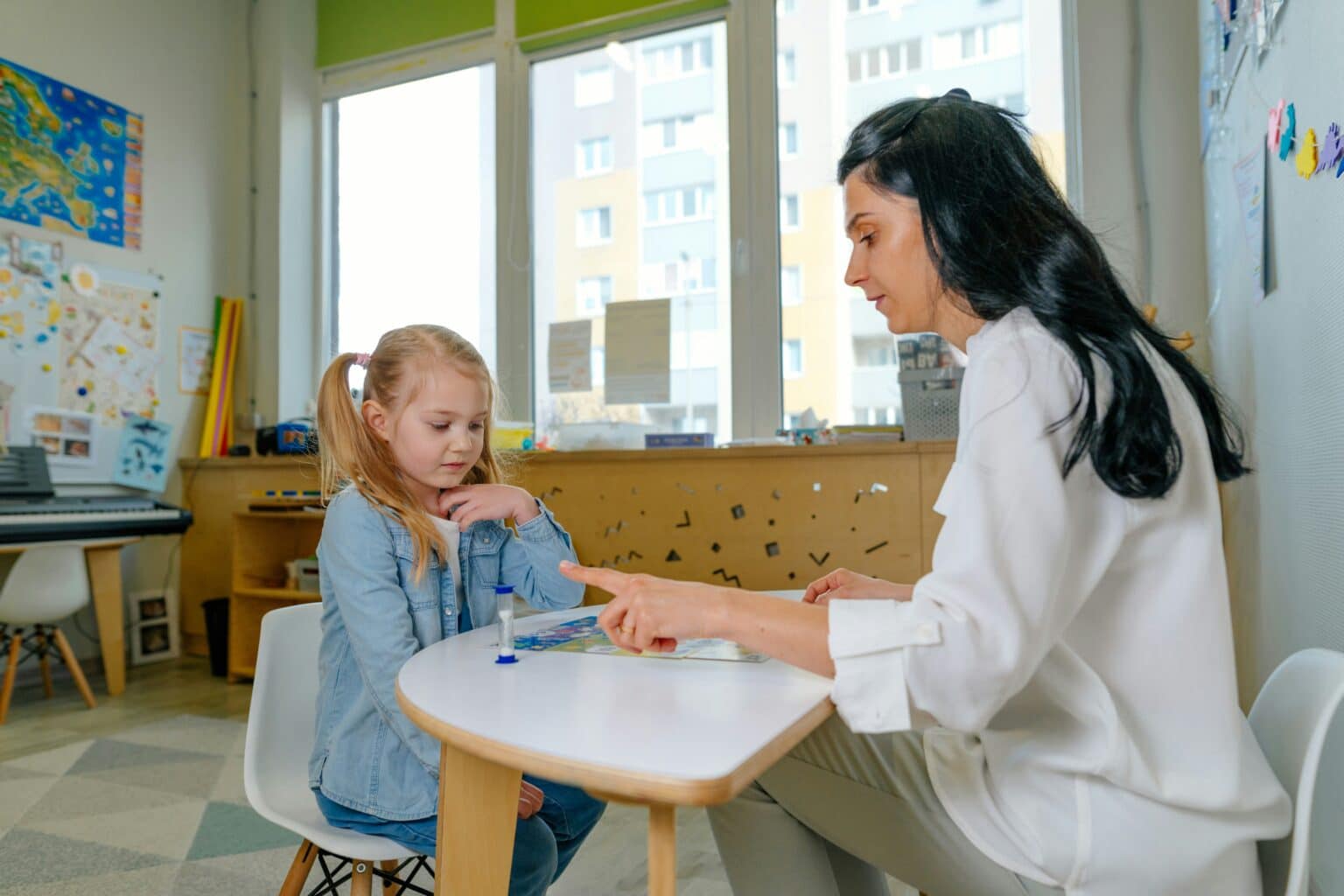 ADHD treatment. Young girl sitting at a desk with a therapist.