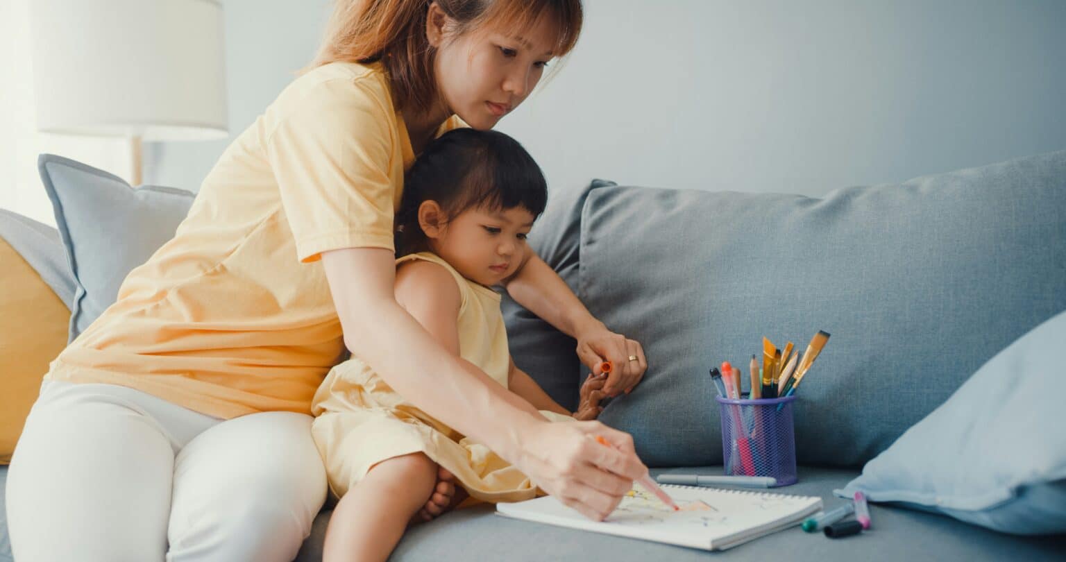 ADHD treatment. Child sitting on a sofa with coloring supplies.