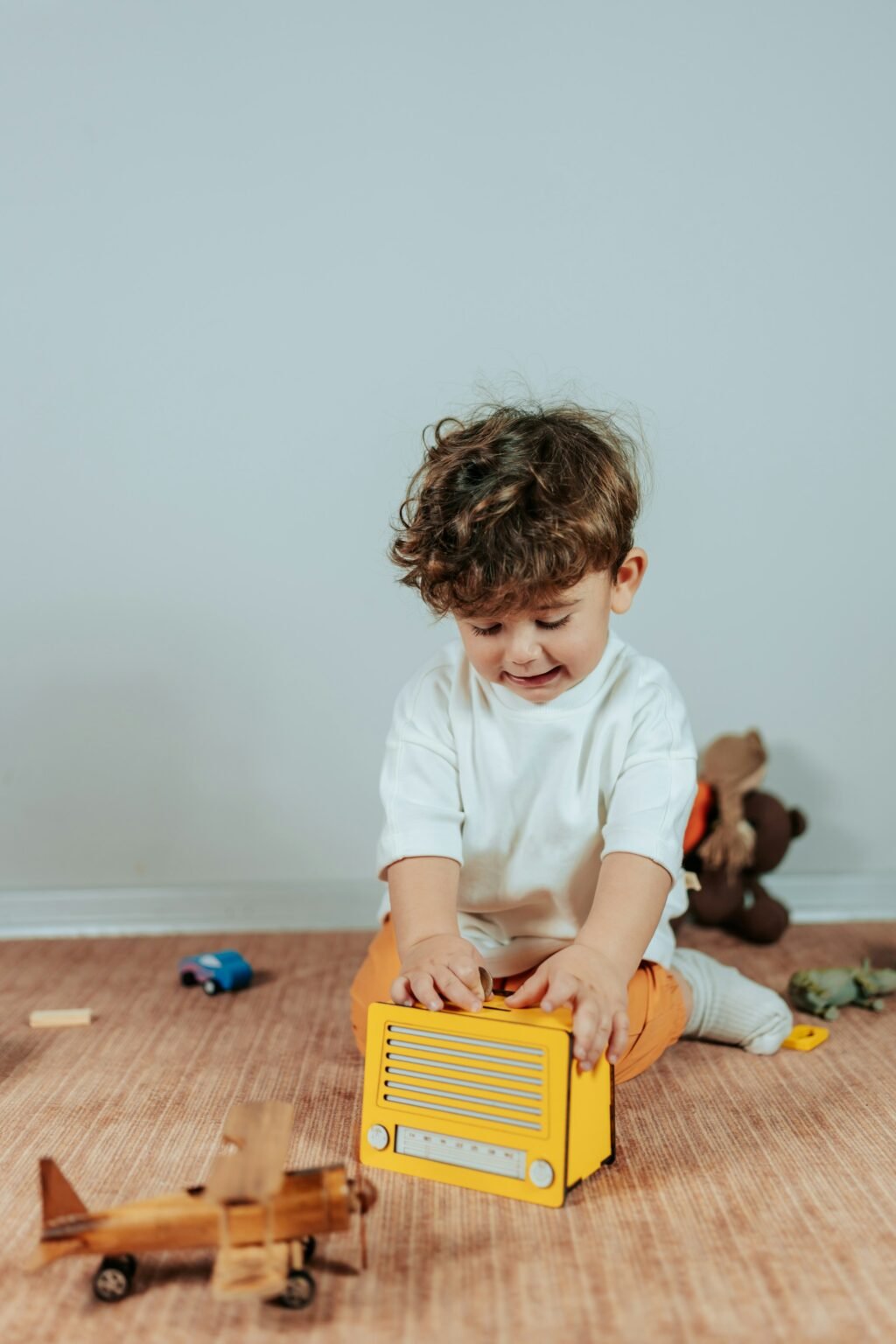 Little boy is in play room playing with yellow box.